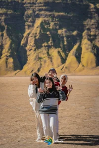 Seorang muda-mudi menikmati wisata Gunung Bromo bersama Surga Wisata, berdiri di tepi kaldera Bromo sambil menikmati panorama pegunungan dan kabut tipis pagi hari, pengalaman petualangan yang seru dan tak terlupakan